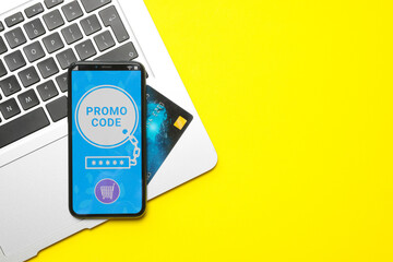 Canvas Print - Smartphone with activated promo code, credit card and laptop on yellow background, flat lay. Space for text