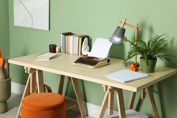 Wall Mural - Writer's workplace with typewriter on wooden desk near pale green wall in room