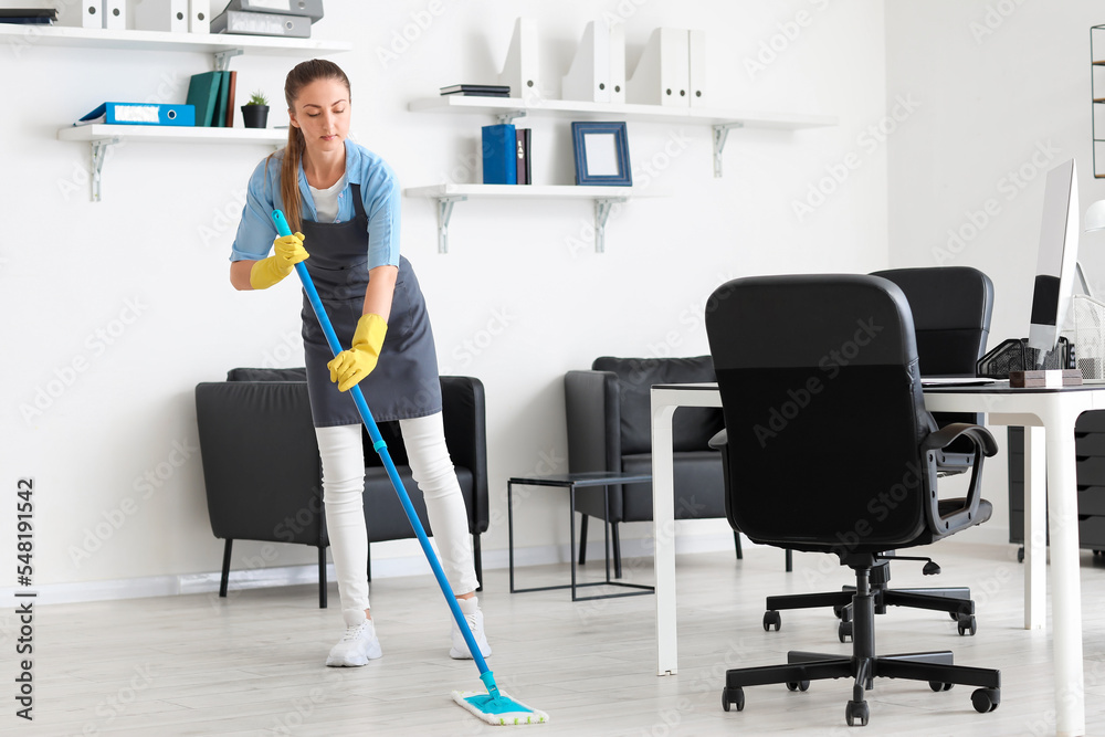 Female worker of cleaning service mopping floor in office