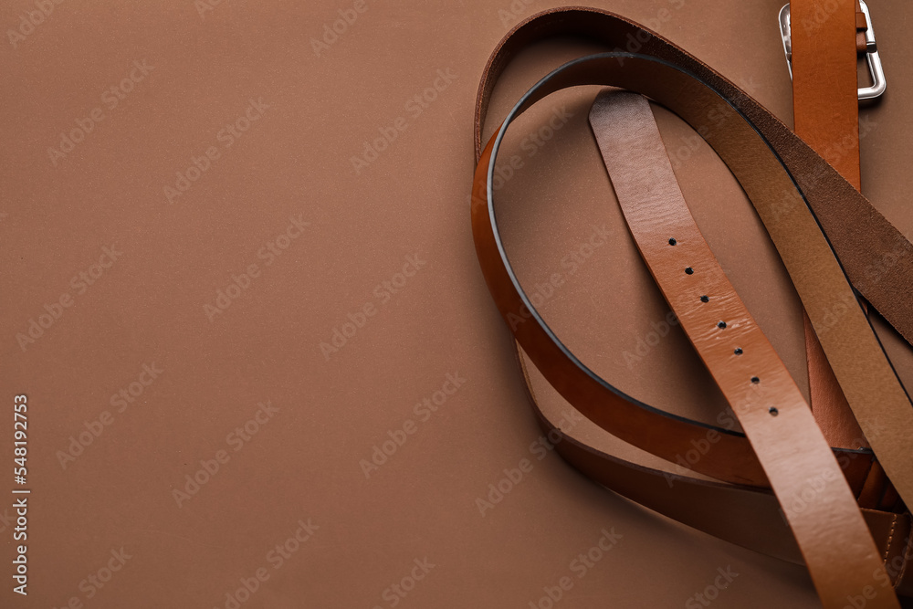 Leather belts on brown background