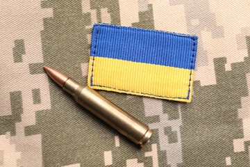 military patch and bullet on pixel ukrainian camouflage, flat lay