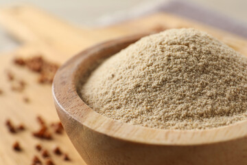 Bowl of buckwheat flour on wooden board, closeup