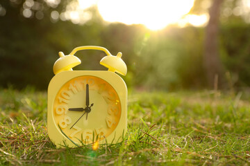 Aufkleber - Yellow alarm clock on green grass outdoors. Space for text