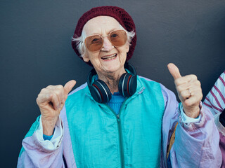 Wall Mural - Senior woman, thumbs up and headphones for stylish fashion, glasses or modern lifestyle and happiness freedom. Yes, hands and streaming music or portrait of happy, funky elderly person with smile