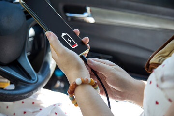 Close up a woman in a white dress charging her mobile phone with car charger cable