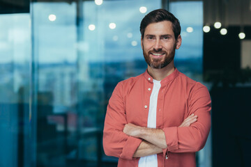portrait of a happy and smiling programmer in the middle of a modern office, a man in glasses and a 
