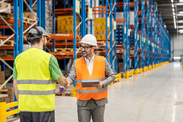 Wall Mural - A supervisor is holding tablet while shaking hands with warehouseman in storage.