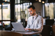 © Dusan Petkovic - Focused young businessman is typing on a laptop while working remotely from coffee shop.