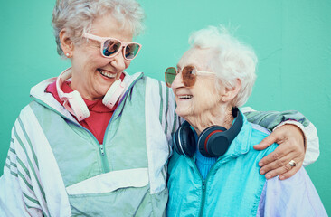 Wall Mural - Happy, fashion and elderly friends hug in cool sunglasses, vintage jackets and modern headphones outdoors. Retro, wall background and senior women hugging with pride, freedom and smile in retirement