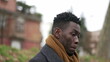 Pensive young black African man standing outside thinking