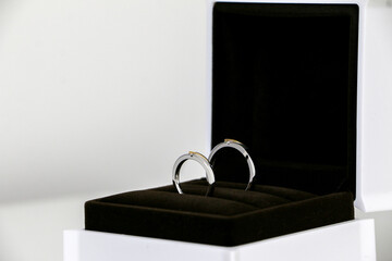 A couple of beautiful his and hers shiny wedding rings displayed in open ring box on the right. Symbol of romance, love and marriage. Selective focus.