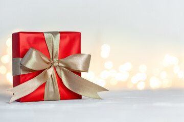 Wall Mural - Gift xmas box wrapped with red paper and bow on festive boke background. Christmas or birthday concept.