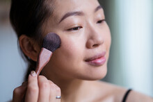Young Asian Woman Applying Foundation On Face With Cosmetic Brush