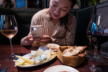 Woman Taking Picture Of Food In Restaurant