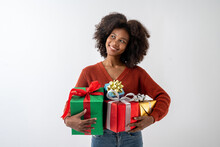 Portrait Of Young Attractive African American Woman With Curly Hair Hugging Gift Boxes In Studio On White Background.