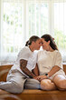 © Brett Edwards/Adobe Stock - Adult lesbian couple cuddle on couch at home in front of window