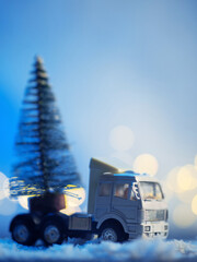 Canvas Print - A small truck is carrying a Christmas tree. Toy conceptual composition