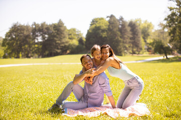 Wall Mural - Happy young family with cute little daughter having fun in the park on a sunny day