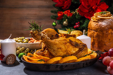 Wall Mural - Christmas or New Year dinner foods on dark table. Set of traditional Xmas party dishes - pannetone, baked chicken, vegetables, potato, cheese and fruits plate, top view copy space