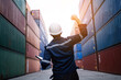 © KANGWANS - Engineer or foreman controls loading of containers from cargo ship for import export, worker checking container load, logistics concept Import export industry, success concept