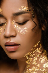 close up of curly african american woman with golden paint on face and neck.