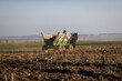 Romanian farmer drives his horse and cart through a field during a sunny autumn day.