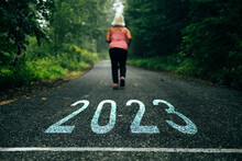 Numbers 2023 Written On The Road Towards New Goals In 2023 And Female Runners Are Starting To Run. New Year With New Ambitions, Challenge, Plans, Goals And Visions. 
