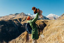 Father Throws Up His Baby Against The Backdrop Of The Mountains