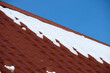 © bilanol - Closeup of house roof top covered with snow in cold winter. Tiled covering of building in wintertime weather