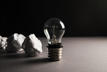 Crumpled Papers And A Light Bulb. Concept Discarded Ideas