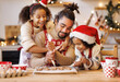 © JenkoAtaman - Happy ethnic family father and two kids in festive outfit making Christmas cookies together in kitchen