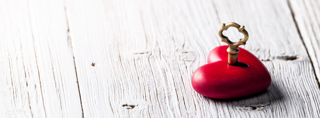 Wall Mural - small hand carved red heart with golden key on rustic wooden table - the key to your heart concept