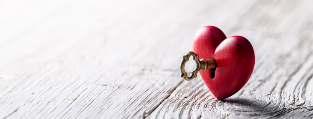 Wall Mural - small hand carved red heart with golden key on rustic wooden table - the key to your heart concept