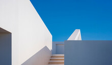 Minimal Exterior Architecture Background, Sunlight And Shadow On Surface Of Stairway To Rooftop Of Modern White Building Against Blue Clear Sky