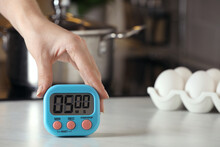 Woman Winding Up Kitchen Timer At White Table Indoors, Closeup. Space For Text