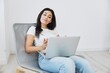 © SHOTPRIME STUDIO - Woman relaxing at home sitting in a chair with a laptop, lifestyle home mood. Mockup, free copy space