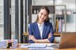 © David - Brown haired smiling Asian woman looking at camera while working in office