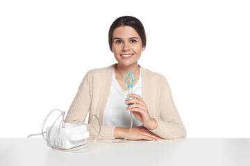 Poster - Happy young woman with nebulizer at table on white background