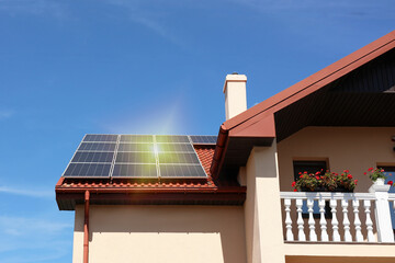 Wall Mural - House with installed solar panels on roof under blue sky. Alternative energy source