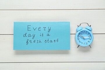 Wall Mural - Phrase Every Day Is A Fresh Start and alarm clock on white wooden table, flat lay. Motivational quote