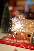 Burning Sparkler Against Backgrond On Decorated Christmas Gingerbread House In Homely Cozy Atmosphere.