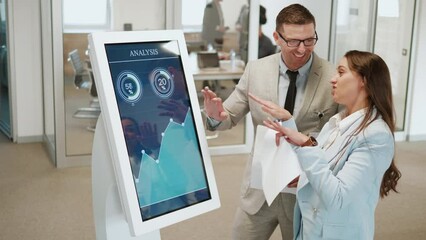Handsome man and businesswoman using digital media graphs and charts screen modern panel in a company at work