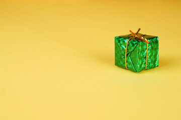 green gift box with gold string bow isolated on yellow background
