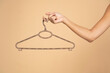 © vladimirfloyd - Woman finger holding empty hanger on a beige studio background