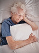 Relax, bedroom and old woman sleeping in peace resting in a house or home dreaming with a soft pillow in hand. Bedding, healthy grandmother or tired elderly person in retirement enjoys napping alone