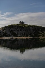 Wall Mural - Green valley and Lake Olbe in mountainous environment under dense clouds reflected in water, Italy