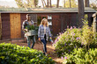 © StratfordProductions - Young multiracial couple in checked shirts walking with harvest through plant nursery