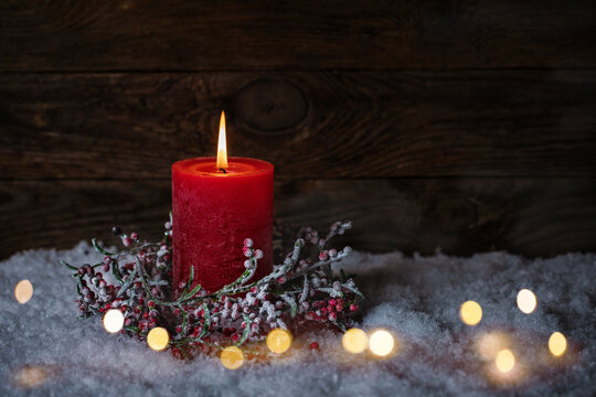 Fototapete - Christmas Candle with decoration in snow landscape with  magic lights. Copy space on dark wood background.