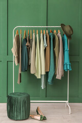 Wall Mural - Rack with clothes, pouf and shoes near green wall