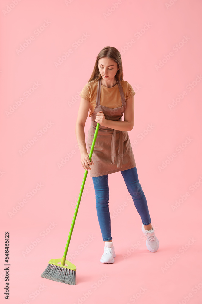 Young woman with mop on pink background